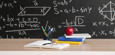 Sınıftaki masada kitap ve okul kırtasiyesi olan elma.