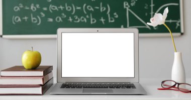 Sınıfta bilgisayar, kitap ve elma öğretmenlerin masasında.