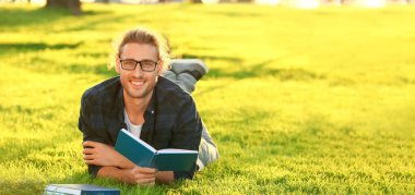 Handsome man reading book in green park