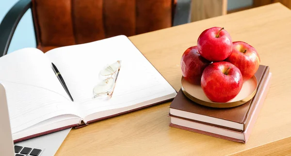 Apples and books on teacher's table in classroom
