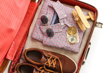 Beyaz arka planda seyahat etmek için erkek aksesuarlarıyla dolu bavul.