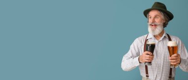 Geleneksel Alman kıyafetleri içinde yakışıklı bir adam ve mavi arka planda bira ve metin için yeri var.