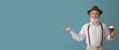 Geleneksel Alman kıyafetleri içinde yakışıklı bir adam ve mavi arka planda bira ve metin için yeri var.