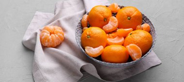 Gri arkaplanda bir kase tatlı mandalina