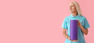 Olgun kadın pembe arka planda köpük rulo tutan metin için boşluk ile