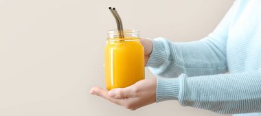 Hafif arka planda sağlıklı zerdeçal içeceği kavanozu olan kadın.