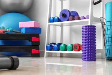 Işık duvarının yanında dambılları olan köpük rulo ve raf ünitesi.