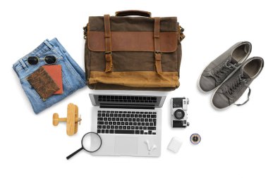 Beyaz arka planda dizüstü bilgisayar ve kulaklıkla seyahat için aksesuarlar