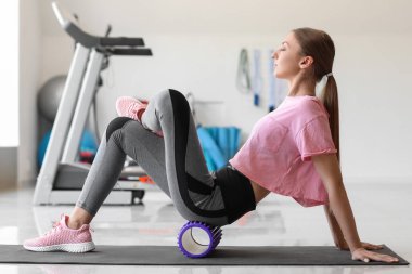 Spor salonunda köpük silindirli genç kadın eğitimi.