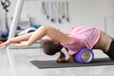 Genç bir kadın spor salonunda köpükle egzersiz yapıyor.