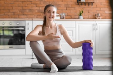 Mutfakta paspasın üzerinde köpüklü tekerlekli sandalyesi olan genç bir kadın.