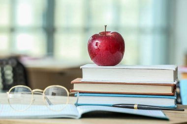 Okul kitapları ve gözlüklü elma sınıfta masanın üzerinde.