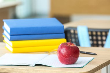 Sınıfta okul kitaplarıyla dolu bir elma, yakın plan.