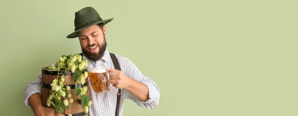 Handsome man in traditional German clothes and with beer on green background with space for text