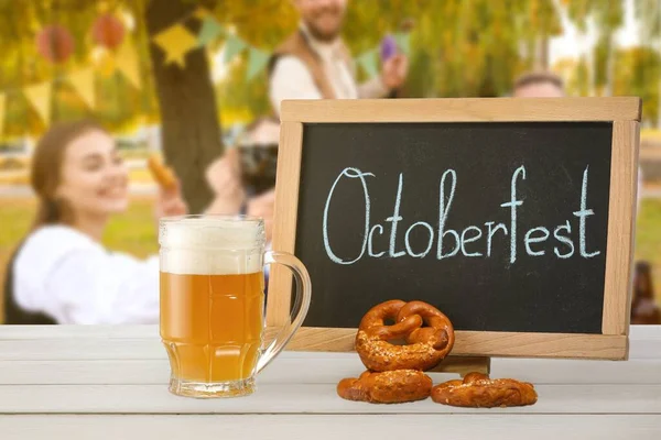 Hrnek Čerstvým Pivem Preclíky Tabulí Slovem Octoberfest Stole Venku — Stock fotografie