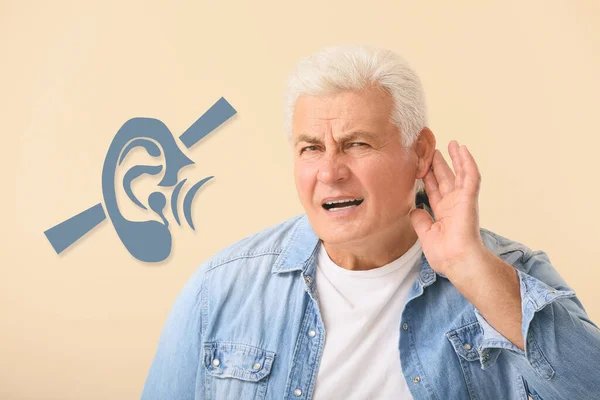 Mature man with hearing problem on beige background