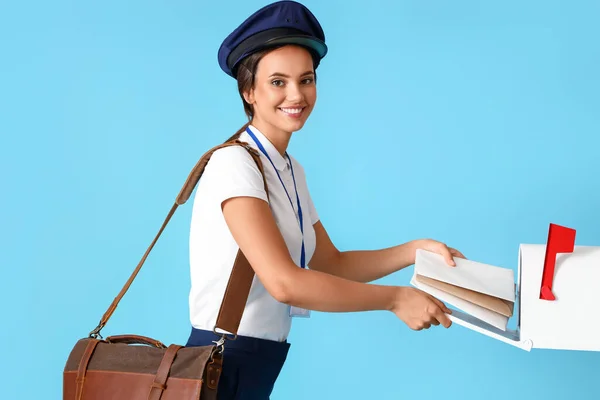 Young Postwoman Putting Letters Mailbox Blue Background — Φωτογραφία Αρχείου