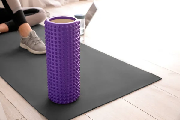 Foam roller on fitness mat in room, closeup
