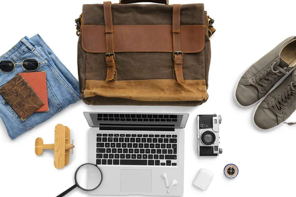 Beyaz arka planda dizüstü bilgisayar ve kulaklıkla seyahat için aksesuarlar