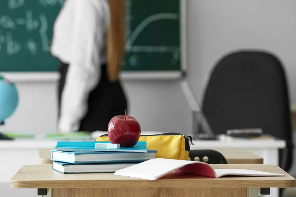 Apple with books and pencil case on table in classroom