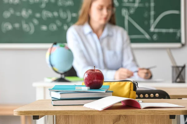 Apple with books and pencil case on table in classroom