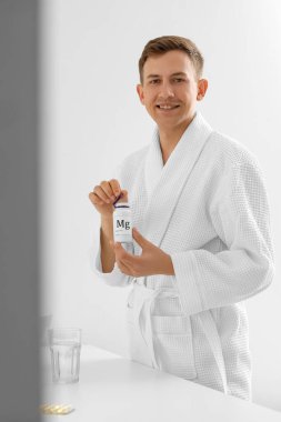 Banyoda elinde magnezyum hapları olan genç bir adam.