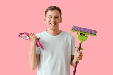 Lastik eldivenleri ve pembe arka planı olan genç bir adam.