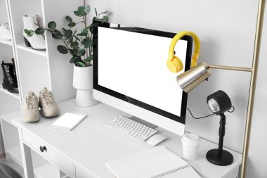 Beyaz duvarın yanında ayakkabısı ve bilgisayarı olan modern işyeri