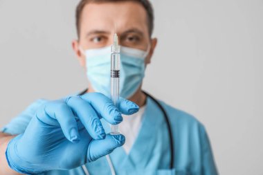 Doctor with syringe on light background, closeup