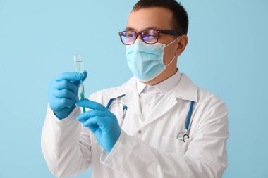 Doctor with ampule and syringe on light blue background