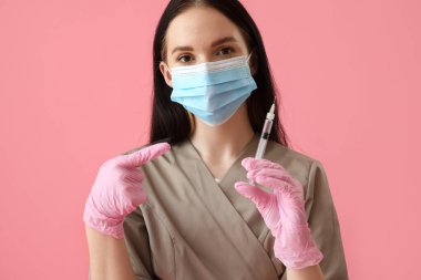 Pembe arka planda şırıngası olan doktor.