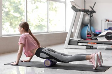 Spor salonunda köpük silindirli genç kadın eğitimi.