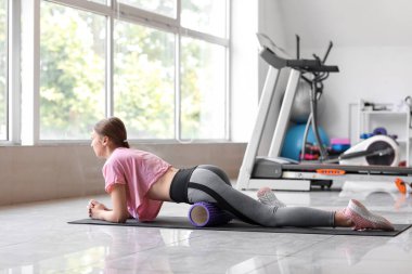 Spor salonunda köpük silindirli genç kadın eğitimi.