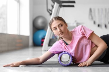 Genç bir kadın spor salonunda köpükle egzersiz yapıyor.