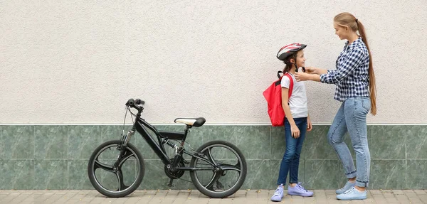 Mother Helping Little Schoolgirl Put Bicycle Helmet Outdoors — Foto de Stock