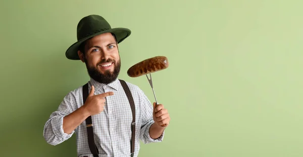 Funny man with big head in traditional German clothes and with sausage on green background. Octoberfest celebration