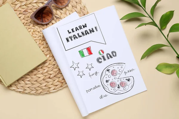 Notebook with text LEARN ITALIAN on beige background, top view