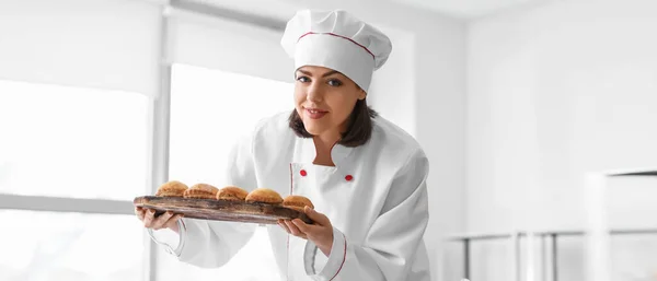 Female baker with tasty pastry in kitchen