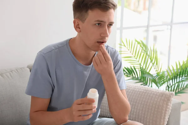 Young man taking vitamin supplement at home