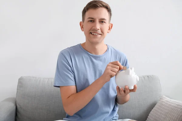 Young Man Putting Coin Piggy Bank Home — Stock Photo, Image