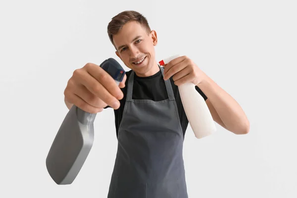 Young Man Spray Bottles Detergent White Background — Stockfoto