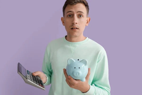 Upset Young Man Piggy Bank Calculator Violet Background — Stock Photo, Image