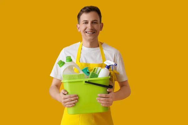 Smiling Young Man Holding Bucket Cleaning Supplies Yellow Background — Fotografia de Stock