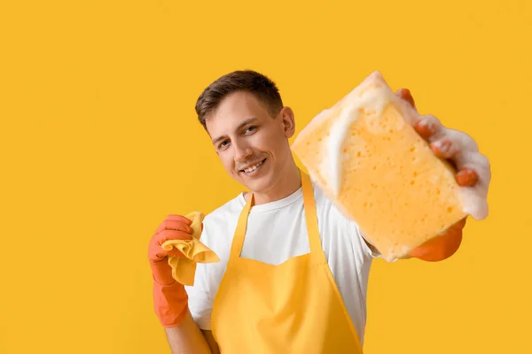 Junger Mann Mit Putzschwamm Und Lappen Auf Gelbem Hintergrund — Stockfoto