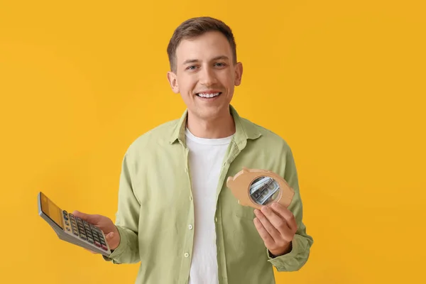 Young Man Piggy Bank Calculator Yellow Background — Stock Photo, Image