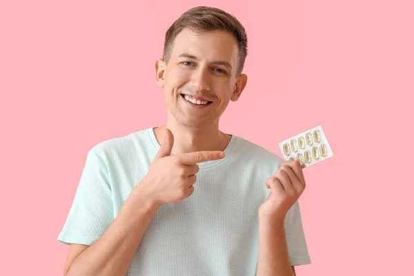 Young Man Pointing Blister Pills Pink Background — Φωτογραφία Αρχείου