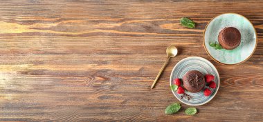 Lezzetli lav keki ve ahududu ile ahşap zemin üzerinde tabaklar ve metin için yer