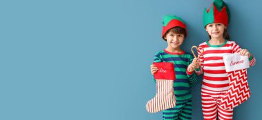 Elf kostümlü şirin çocuklar mavi arka planda Noel çorapları tutuyorlar ve mesaj için yer var.