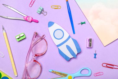 Okul kırtasiyeli kağıt roket ve menekşe arkaplanda gözlük.