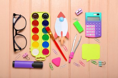 Okul kırtasiyeli kağıt roket ve renkli ahşap arka planda gözlük.